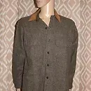 Brown button-up shirt displayed on a mannequin against a patterned wall.