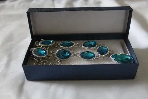 Blue gemstone necklace with silver settings displayed on a black velvet bust stand