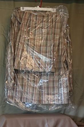 Stack of folded striped fabric wrapped in plastic, hanging against a wall