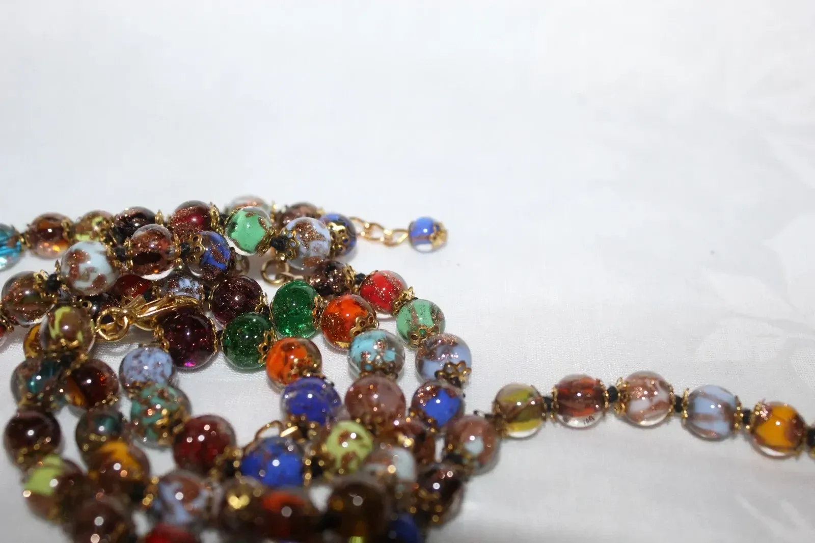 Colorful glass beads strung in a loose pile on a white background