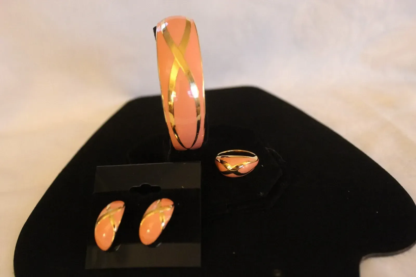 Orange gemstone jewelry set on black display stands, including a bracelet, ring, and earrings.