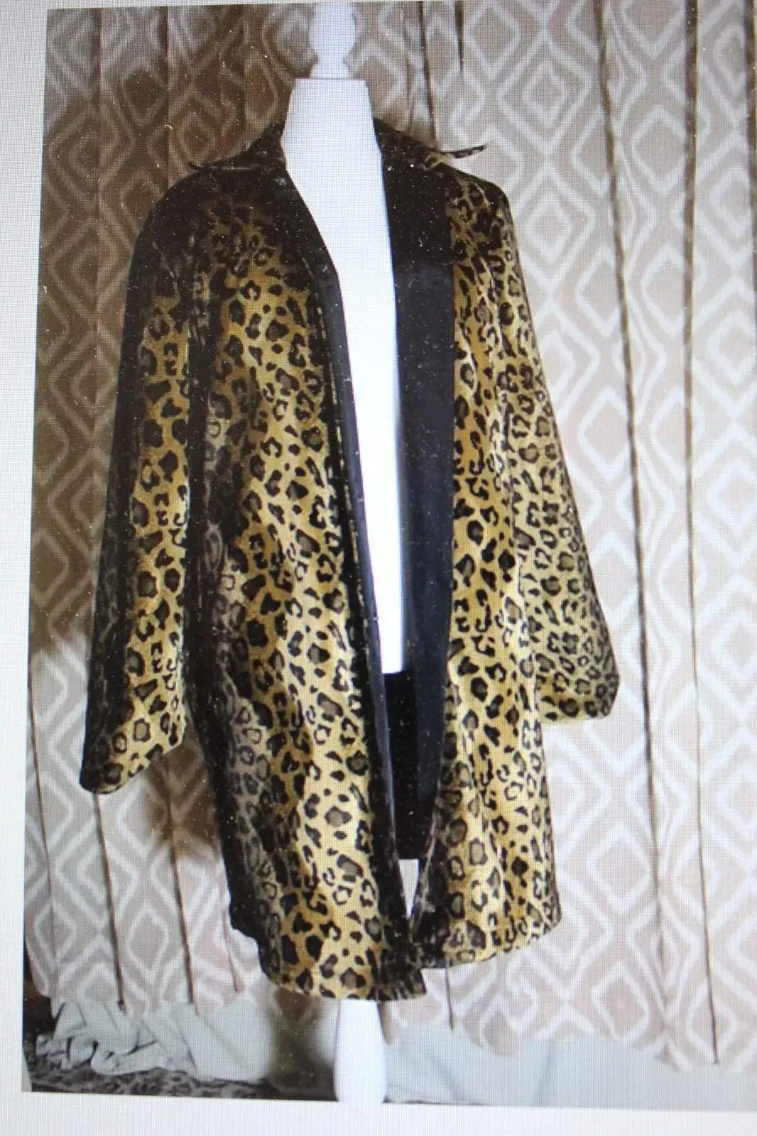 Leopard-print coat on a mannequin against a patterned curtain background