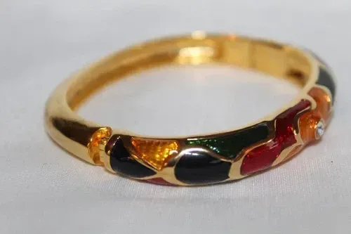 Gold ring with black, red, and green enamel accents on a white background