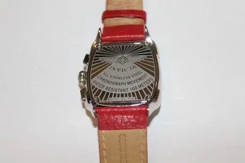 Red wristwatch with a pink face and silver case against a dark background