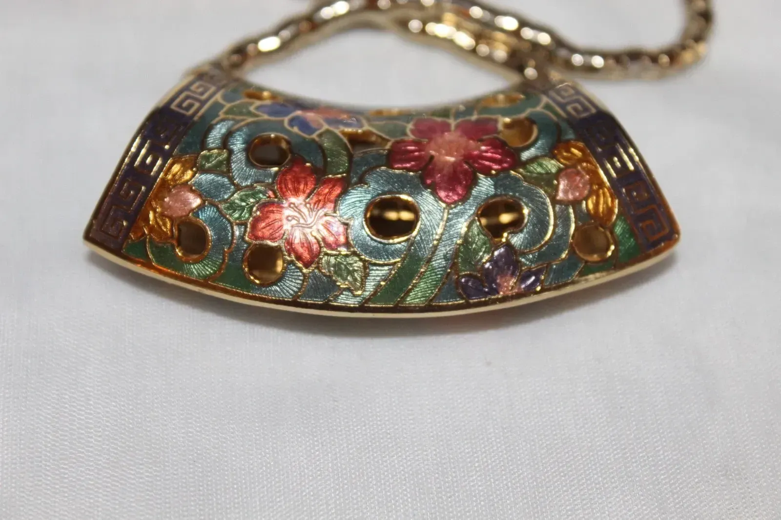 Colorful floral enamel pendant necklace with gold chain on a white background