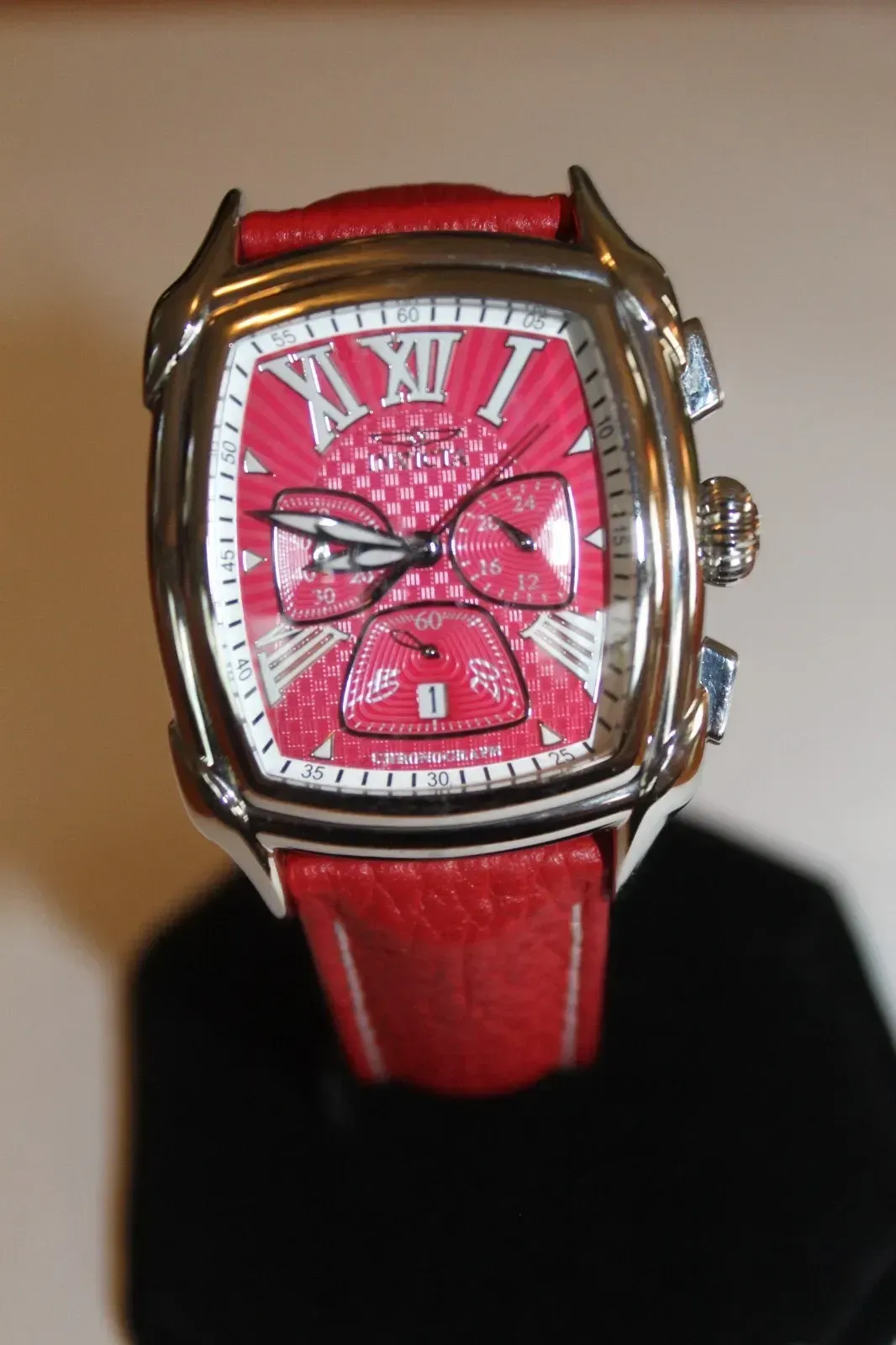 Red wristwatch with a pink face and silver case against a dark background