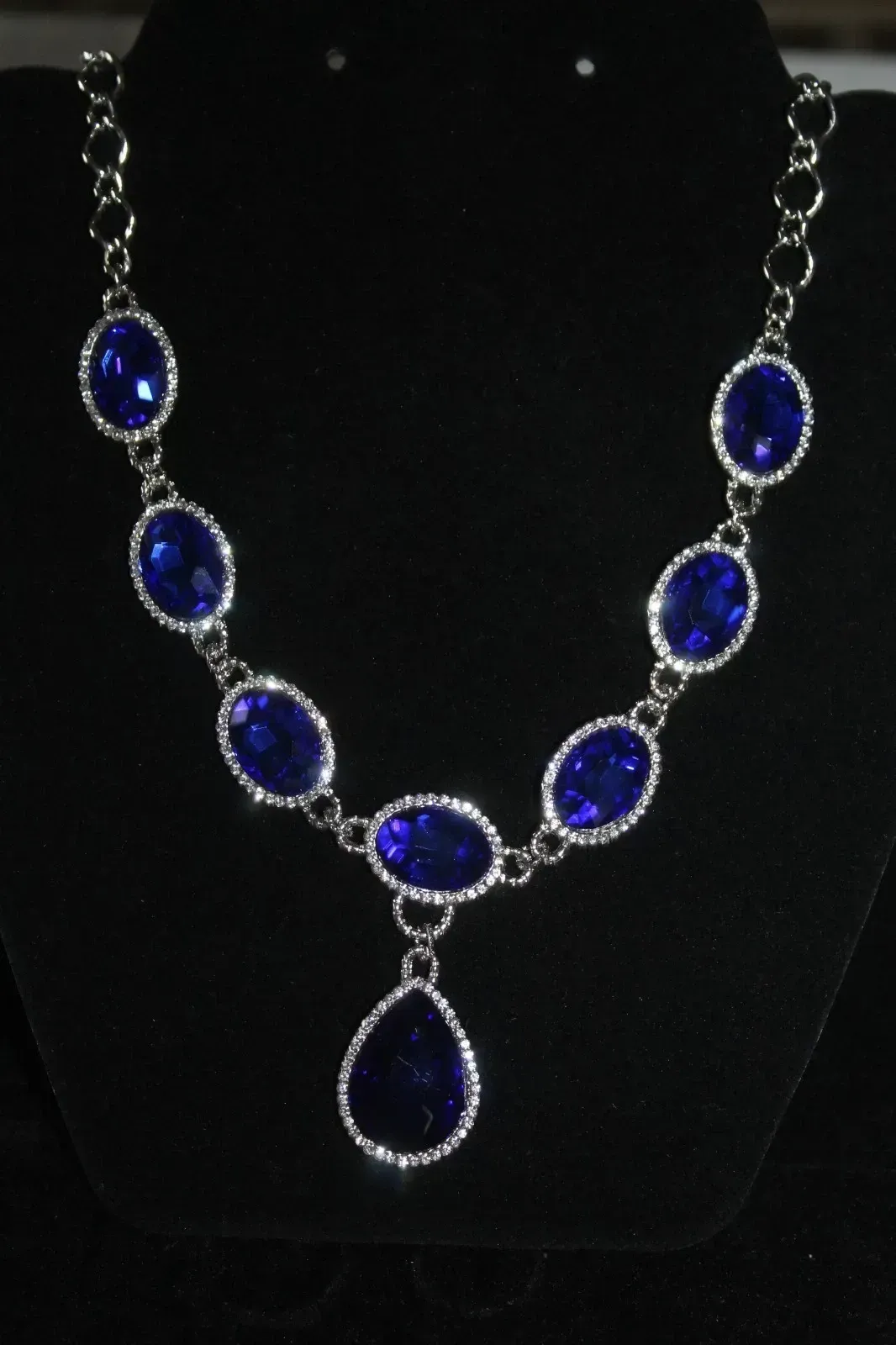 Blue teardrop gemstone necklace on a black display bust
