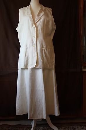 White sleeveless dress on a mannequin against a dark background.
