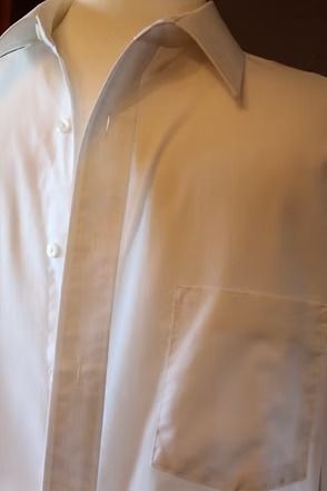 White button-up dress shirt with a collar and chest pocket on a hanger or person’s torso.