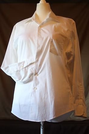 White button-up shirt with a large sleeve cutout, displayed on a mannequin against a dark background