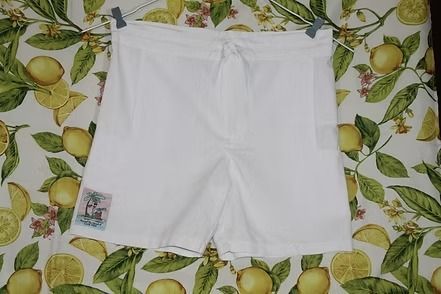 White shorts laid flat on a patterned green-and-yellow leaf-print surface