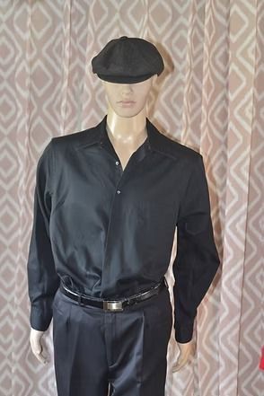 Mannequin wearing black shirt, trousers, belt, and beret against patterned curtain backdrop