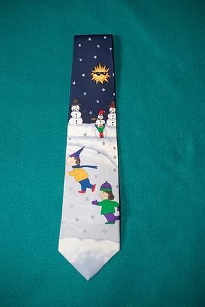 Winter scene on a blue necktie, with snowmen, children sledding, and a bright sun in the sky