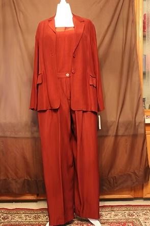 Red two-piece suit on a mannequin against a brown curtain background.
