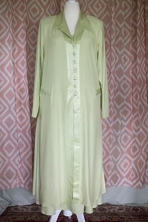 Light green long coat with matching dress displayed on a mannequin against a patterned curtain.