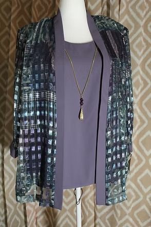 Mannequin wearing a purple top, patterned teal-black jacket, and long pendant necklace