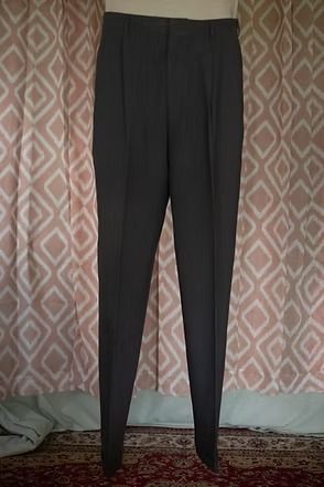Black wide-leg pants hanging against a patterned wall.