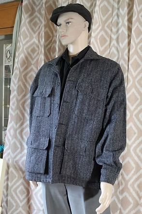 Mannequin wearing a dark cap and gray textured jacket against patterned curtains