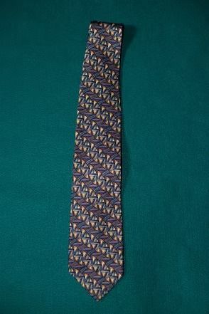 Patterned necktie on teal fabric background