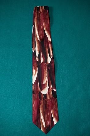 Maroon patterned necktie with white and tan leaf-like shapes on a teal background