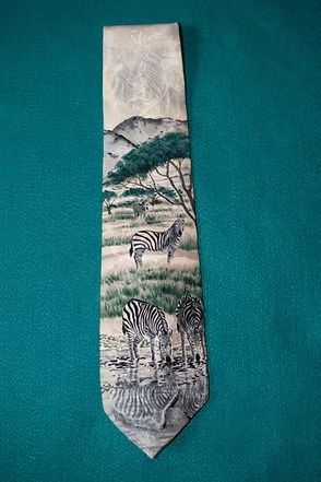 Narrow tie with zebra and tree landscape pattern in muted gray, green, and black