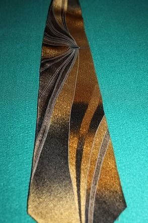Close-up of a patterned gold and black necktie on a teal background