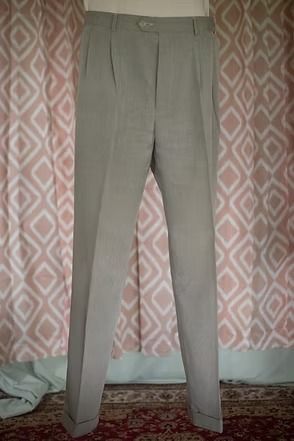 Gray trousers hanging against a patterned curtain indoors
