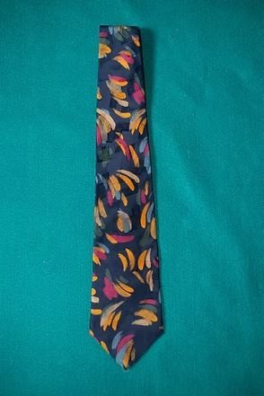 Patterned navy necktie with colorful leaf design on a teal background