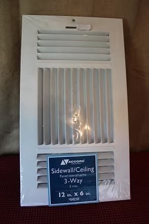 White 3-way sidewall ceiling vent register with adjustable louvers, in packaging on a wooden surface