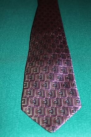A patterned purple tie with pink and black geometric designs on a teal background