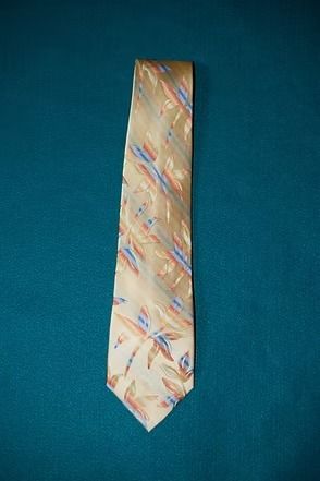 Patterned beige necktie with blue and red diagonal stripes on a teal background