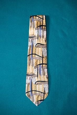 Patterned necktie with tan, blue, and black geometric design on a teal background