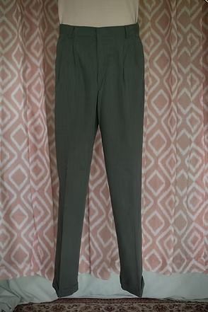 Dark green trousers hanging in front of a pink patterned curtain.