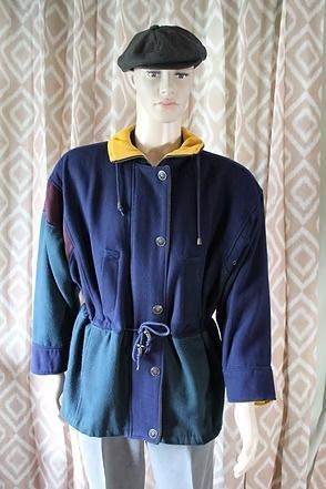 Mannequin wearing a navy jacket with yellow lining, black cap, and black shirt in front of curtains