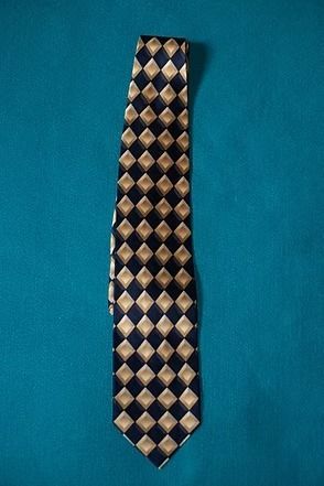 Blue and beige diamond-patterned necktie on a teal background