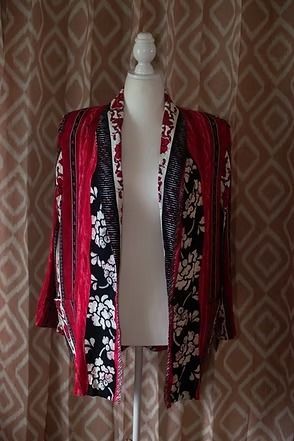 Red, black, and white patterned jacket on a mannequin against a patterned curtain backdrop