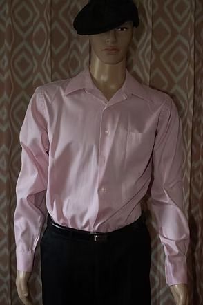 Mannequin wearing a pink dress shirt, black pants, and black beret against a patterned backdrop