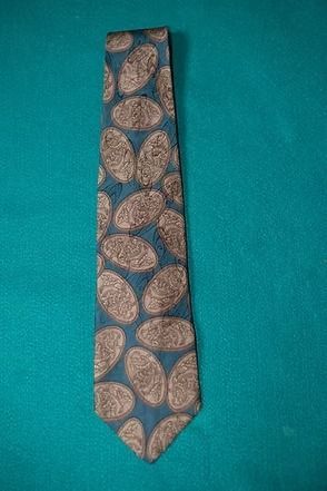 Blue patterned necktie with tan leaf design on a teal background