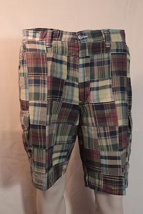 Plaid cargo shorts in red, green, and beige hanging against a plain wall