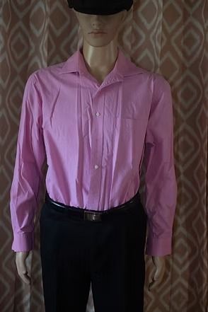 Side-view mannequin wearing a pink shirt, black cap, and black pants against a patterned curtain.
