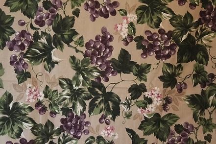 Patterned wallpaper with green leaves and clusters of purple flowers on a beige background