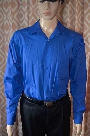 Mannequin wearing a bright blue long-sleeve dress shirt and black trousers against a patterned curtain background
