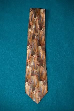 Patterned gold and brown necktie on a teal background
