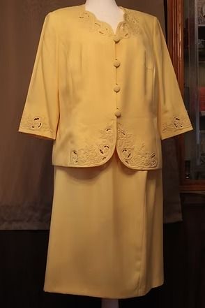 Yellow embroidered two-piece suit with buttoned jacket and long skirt on a mannequin