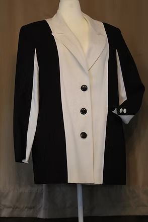 Black-and-white tailored blazer on a mannequin, with contrasting white lapels and cuffs and three buttons.