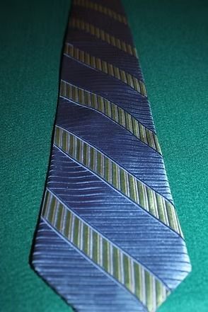 Blue striped necktie with diagonal green and purple stripes on a teal background