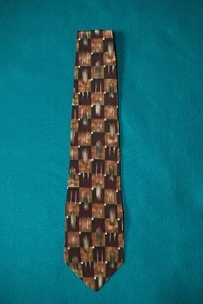 Patterned brown and tan necktie on a teal background