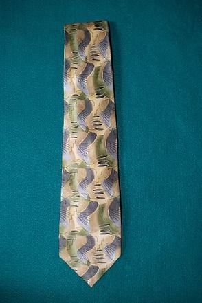 Patterned necktie with blue, green, and beige zigzag design on a teal background