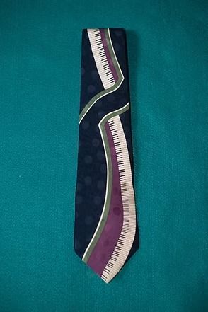 Patterned necktie with purple, white, and green accents on a teal background