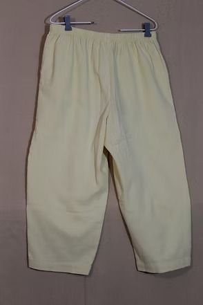 Light cream pants hanging on a gray hanger against a plain background